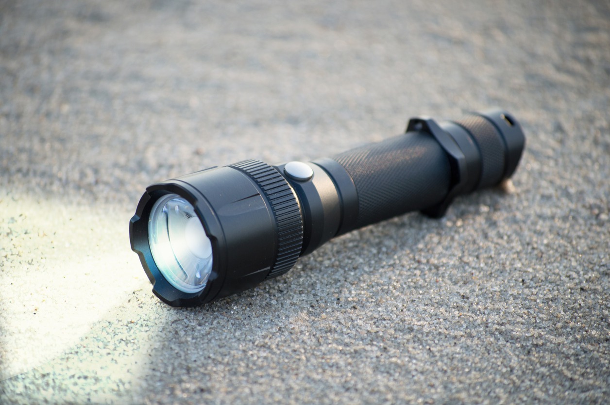 pocket LED flashlight lies on a sand