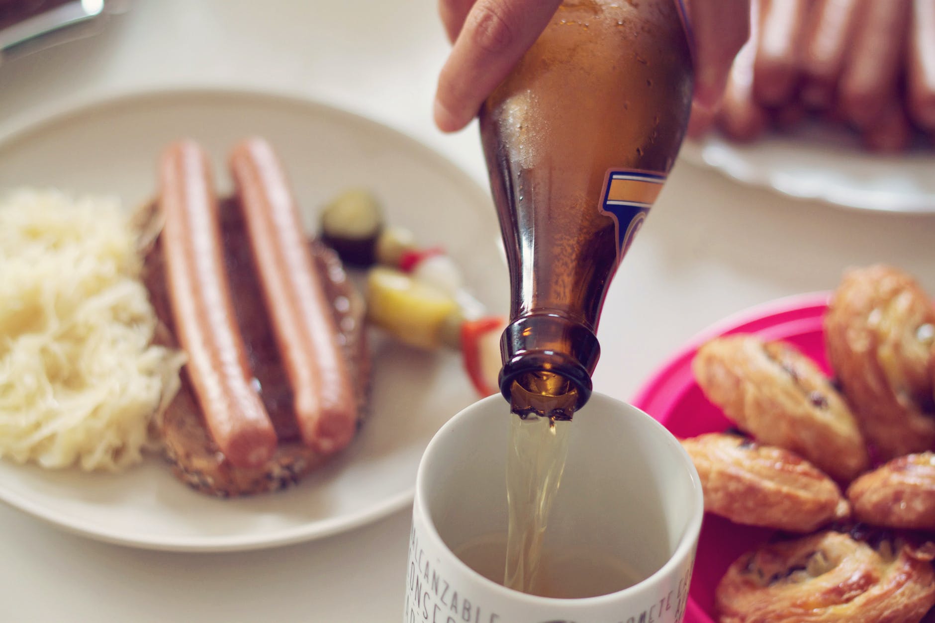 a person pouring beer on a mug, plates full of food