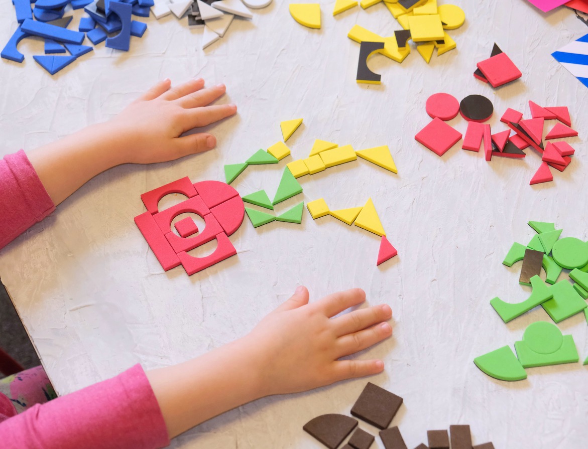 Toddler girl plays with geometric mosaic details. game for creativity. Leisure of child, development of fine motor skills and abstract thinking